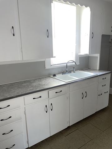 Lima apartment for rent - A kitchen with white cabinets and a sink under a window.