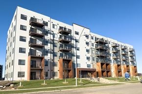 Saskatoon apartment for rent - A large white apartment building with balconies and a blue sky in the background.