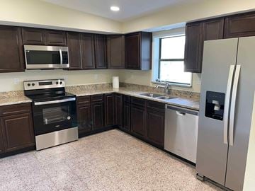 Orlando house for rent - A kitchen with dark brown cabinets and stainless steel appliances.