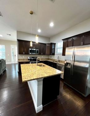 Orlando house for rent - A kitchen with dark wood cabinets and a granite countertop.