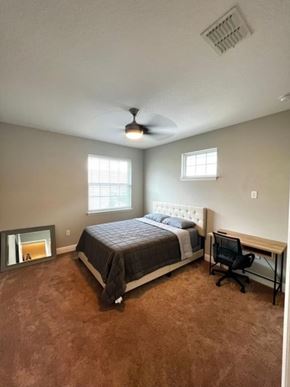 Orlando house for rent - A bedroom with a bed, desk, and fan.