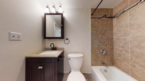 Pepperell apartment for rent - A bathroom with a toilet, sink, and mirror.