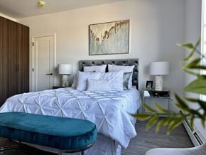 Saskatoon apartment for rent - A bedroom with a large bed and a painting on the wall.