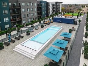 Saskatoon apartment for rent - A large outdoor swimming pool surrounded by lounge chairs and umbrellas.