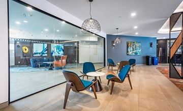 Saskatoon apartment for rent - A modern living room with blue chairs and a glass wall.