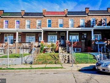 Baltimore apartment for rent - a brick house with stairs and a fence in front of it