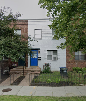 Washington apartment for rent - A white and red brick house with a blue door and a black trash can.
