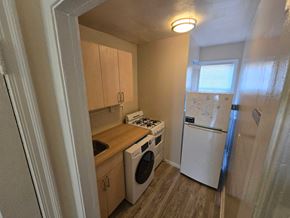 Washington apartment for rent - A small kitchen with a white fridge, a white stove, and a white dishwasher.