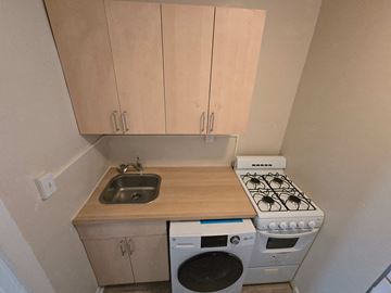 Washington apartment for rent - A small kitchen with a stove, sink, and washer.