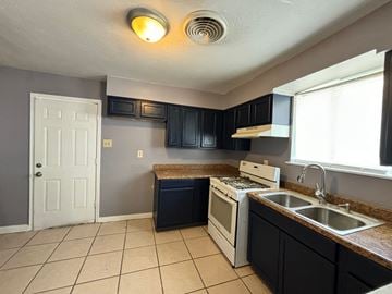 New Orleans apartment for rent - a kitchen with black cabinets and a sink and a stove