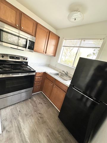Lafayette apartment for rent - A black refrigerator is in a kitchen with wooden cabinets and a stove.