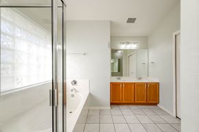 Pflugerville apartment for rent - A white bathroom with a tub, sink, and mirror.
