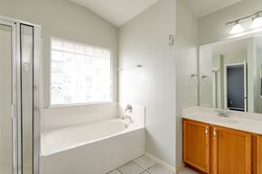 Pflugerville apartment for rent - A white bathroom with a tub, sink, and mirror.