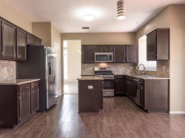 Cedar Park apartment for rent - A kitchen with dark brown cabinets and a black refrigerator.