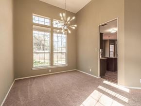 Cedar Park apartment for rent - A room with a carpeted floor, a chandelier, and a view of trees through the windows.