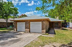 Austin apartment for rent - A house with a white garage door is surrounded by greenery.