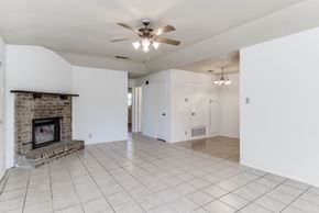Austin apartment for rent - A spacious living room with a fireplace and a ceiling fan.