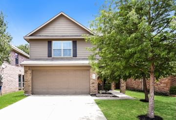 Houston apartment for rent - a tan house with a garage door and a tree