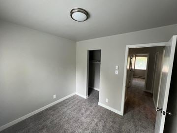 Fort Collins apartment for rent - a living room with gray carpet and a door to a hallway