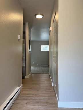 Fort Collins apartment for rent - a hallway with white walls and a wood floor and a door to a bedroom