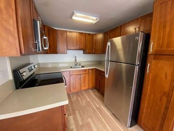 Honolulu apartment for rent - A kitchen with wooden cabinets and a stainless steel refrigerator.