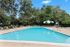 Rockville apartment for rent - a swimming pool with a green and white umbrella and chairs around it