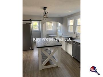 Knoxville house for rent - A kitchen with a table in the middle and a logo of Key Properties LLC.