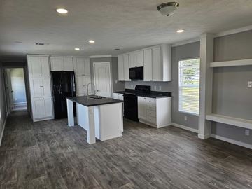 Shawnee house for rent - A kitchen with white cabinets and a black fridge.