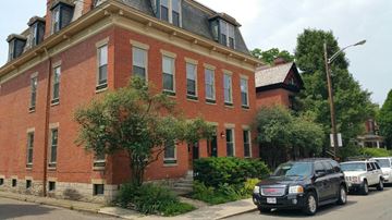 Columbus apartment for rent - A black car is parked on the side of a street in front of a red brick building.