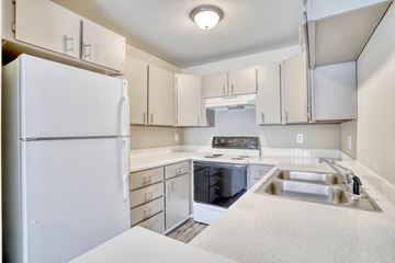 Longmont apartment for rent - a kitchen with white cabinets and a sink and a refrigerator