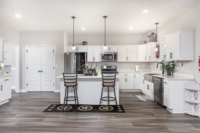 Clarksville house for rent - a kitchen with white cabinets and a island with two chairs