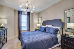 Flower Mound apartment for rent - A bedroom with a large bed and a chandelier.