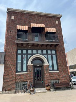 Grinnell apartment for rent - A red brick building with a black door and a balcony with orange awnings.