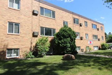 Moorhead apartment for rent - a brick building with grass and trees in front of it