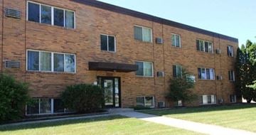 Moorhead apartment for rent - a brick apartment building with a lawn and a sidewalk