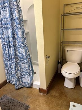 Grinnell apartment for rent - A white toilet sits next to a shower curtain in a bathroom.