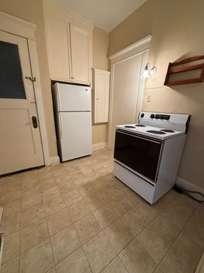 Grinnell apartment for rent - A white fridge and stove in a kitchen with beige tiles.