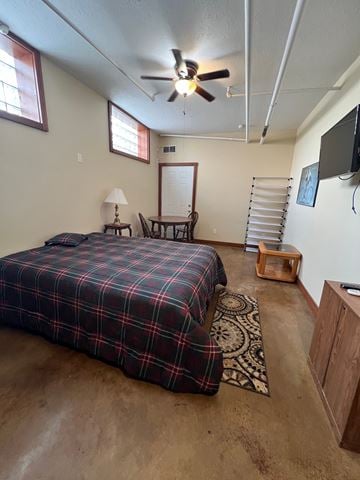 Grinnell apartment for rent - A bedroom with a bed, a chair, a table, a lamp, a ceiling fan, and a wall-mounted TV.