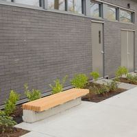 Victoria apartment for rent - A grey building with a bench in front of it.