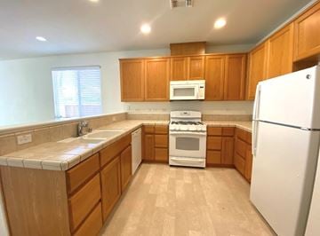 Merced house for rent - A kitchen with wooden cabinets and a white refrigerator.
