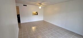Plantation apartment for rent - A spacious room with a ceiling fan and a small mirror on the wall.