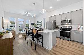 Austin apartment for rent - an open kitchen and dining area with a white counter top and stainless steel appliances
