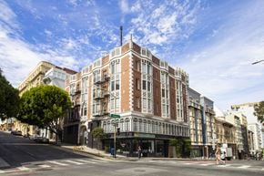 San Francisco apartment for rent - A street view of a large, multi-story building with a red brick facade and white trim.