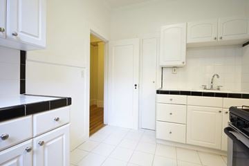 San Francisco apartment for rent - A kitchen with white cabinets and black countertops.