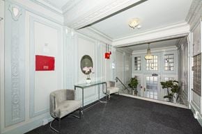 San Francisco apartment for rent - A grey armchair sits in a room with a glass table and a chandelier.
