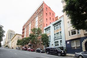 San Francisco apartment for rent - Cars parked on the side of a street in front of a red building.