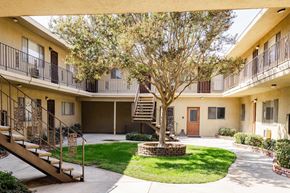 Whittier apartment for rent - A courtyard with a tree, a staircase and a building in the background.