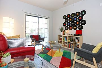 Chandler apartment for rent - A living room with a red couch, a glass table, and a bookshelf with records on it.