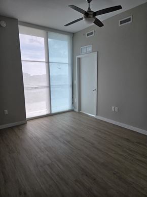 Miami apartment for rent - A room with a ceiling fan and sliding glass doors.