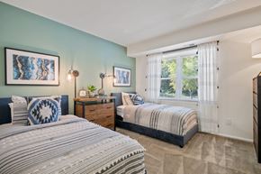 Windsor Mill townhouse for rent - A bedroom with two beds and a nightstand with a plant on it.